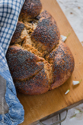 Overhead view of plaited bread with poppy seeds on a breadboard photo