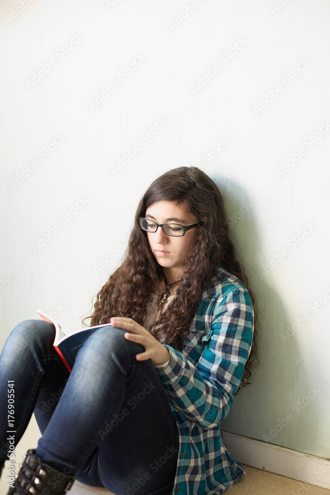 Young woman sitting on the floor and reading a book