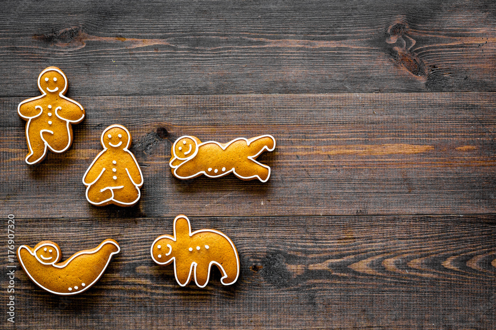 Gingerbread cookies in shape of yoga asanas on dark wooden background top view copyspace Gingerbread cookies in shape of yoga asanas on dark wooden background top view copyspace
