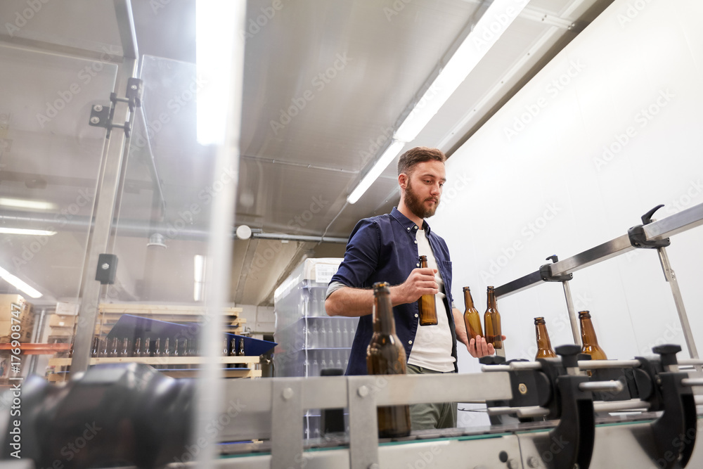 men with bottles on conveyor at craft beer brewery men with bottles on conveyor at craft beer brewery