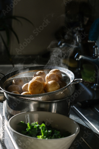 Freshly cooked new potato's with steam coming from them,draining by the kitchen sink. photo