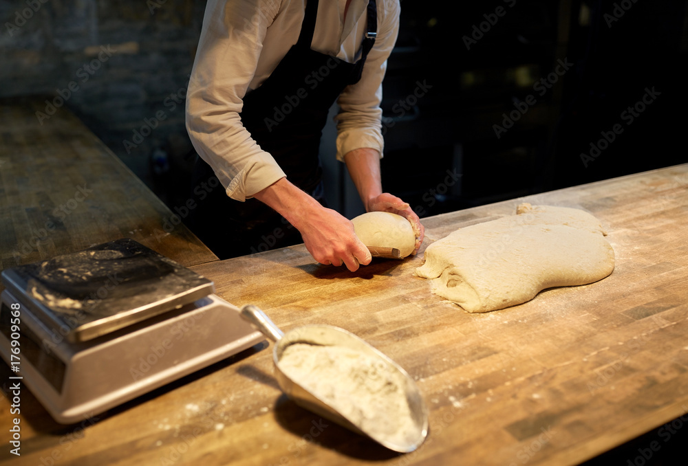 baker portioning dough with bench cutter at bakery baker portioning dough with bench cutter at bakery