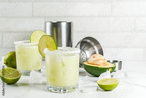 Alcoholic cocktail recipes and ideas. Avocado and lime margarita with salt, on a white marble kitchen table. Copy space
