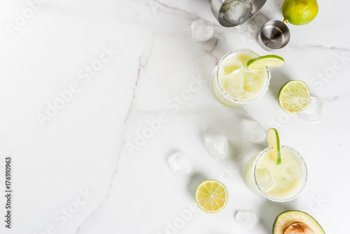 Alcoholic cocktail recipes and ideas. Avocado and lime margarita with salt, on a white marble kitchen table. Copy space top view photo