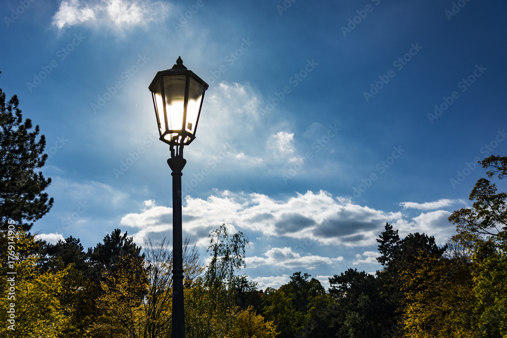 Lighting street lamp under blue sky with fairy tale´s clouds.