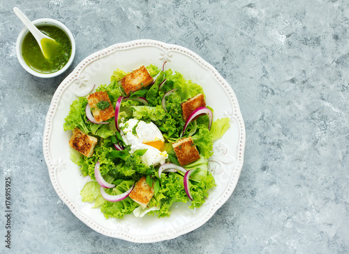 Spring salad with poached egg and crispy croutons. View from above.