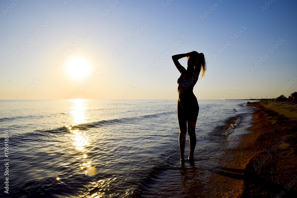 Silhouette of a girl against the sunset by the sea