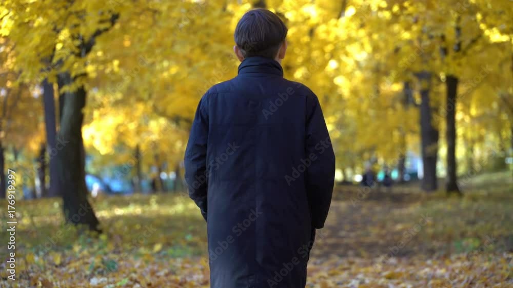 young guy in a black coat in the autumn park young guy in a black coat in the autumn park