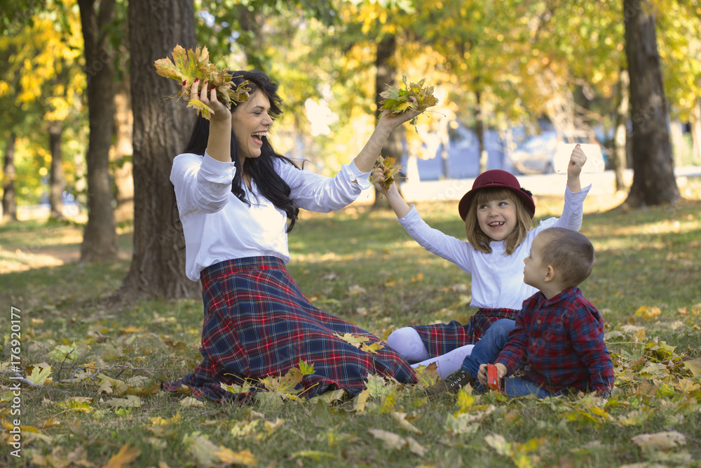 Beautiful young mother plays with her children in the park in autumn