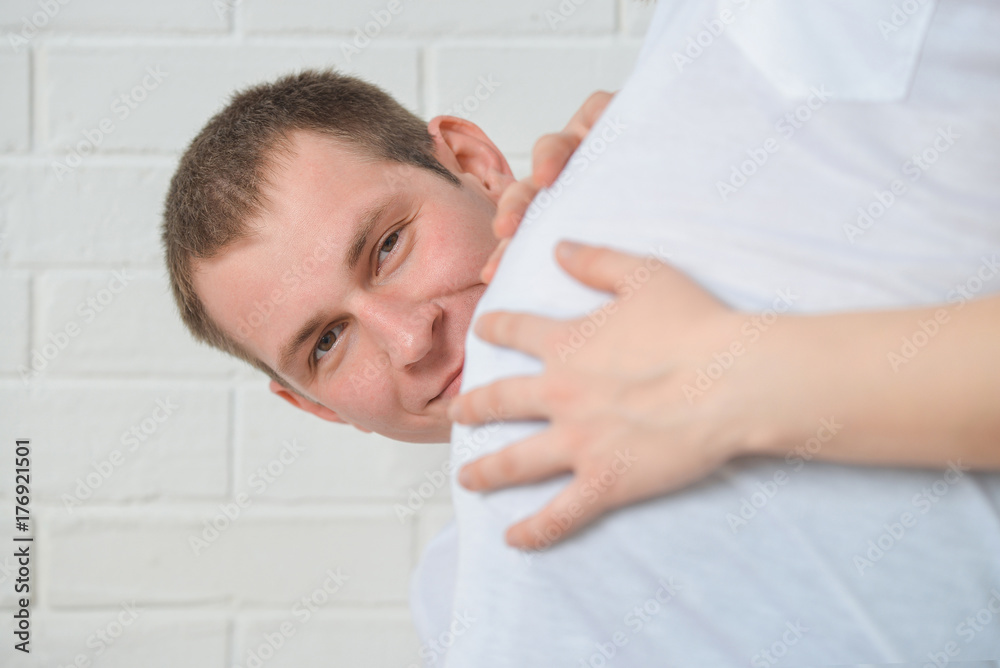 Smiling Man is looking from behind of the belly of his pregnant wife, focus on man Smiling Man is looking from behind of the belly of his pregnant wife, focus on man