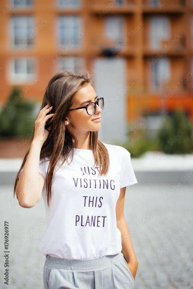 Summer sunny lifestyle fashion portrait of young stylish hipster woman walking on street, wearing cute trendy outfit