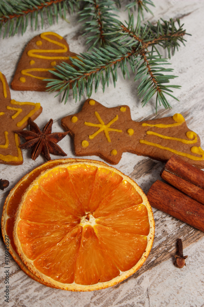 Dried orange, spices and decorated gingerbread on rustic board, Christmas time concept Dried orange, spices and decorated gingerbread on rustic board, Christmas time concept