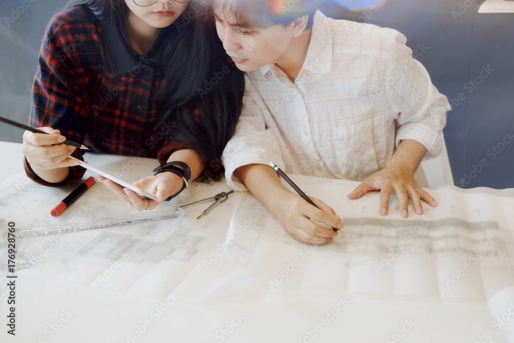 Architect team working on blueprint, Two colleagues interior designer discussing data on blueprint on table for architectural project in office. Architect team working on blueprint, Two colleagues interior designer discussing data on blueprint on table for architectural project in office.