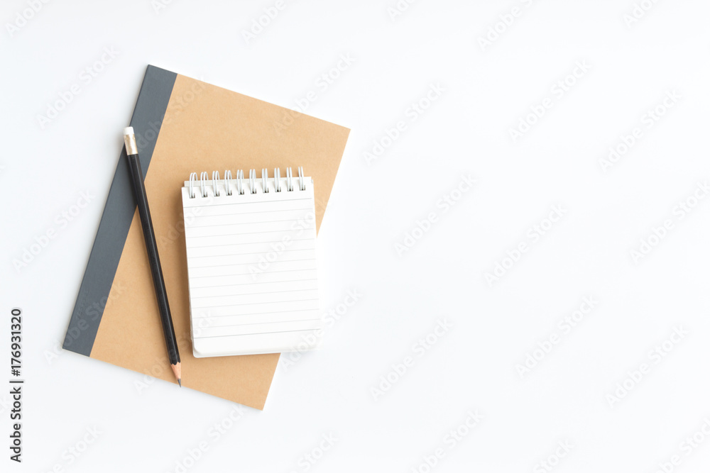 black pencil and notebook paper on brown notebook paper on white background - obrazy, fototapety, plakaty 