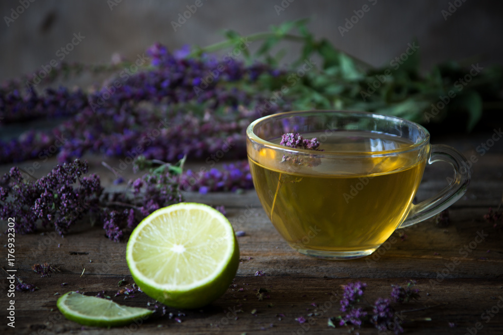 Green tea with herbals and lime. Tea with oregano on the wooden background Green tea with herbals and lime. Tea with oregano on the wooden background