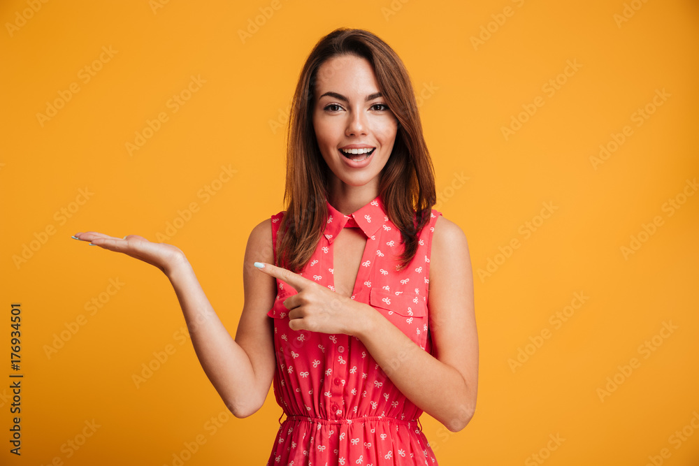Close-up photo of young pretty woman pointing with finger on her empty palm, looking at camera Close-up photo of young pretty woman pointing with finger on her empty palm, looking at camera
