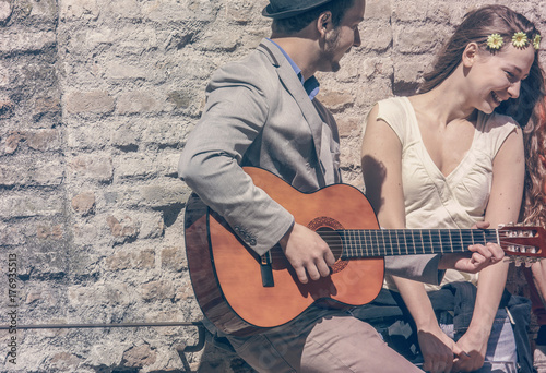romantic young man play guitar sing love song while amused shy girl smiling