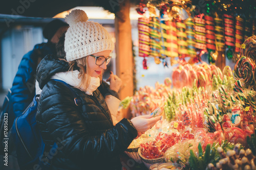 Happy beautiful woman selecting traditional holiday candies on Christmas market