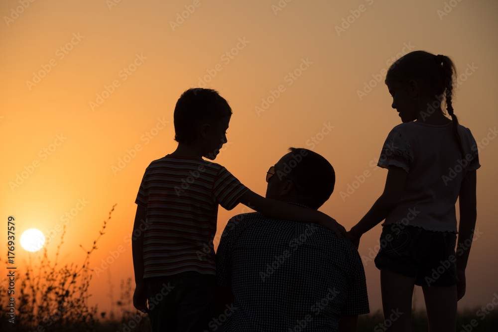 Father and children playing in the park at the sunset time.