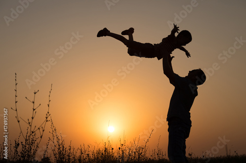 Father and son playing in the park at the sunset time.
