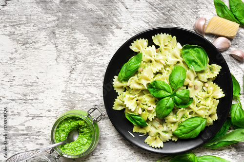 farfalle pasta with basil pesto and herbs in a plate with fork