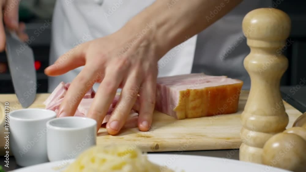 PAN with mid-section of hands of unrecognizable male cook cutting ham on wooden board PAN with mid-section of hands of unrecognizable male cook cutting ham on wooden board