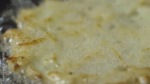 PAN with close up of crispy potato pancake frying in hot vegetable oil photo