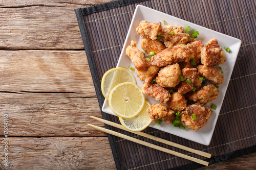 Spicy chicken karaage with lemon and green onion close-up. horizontal top view
