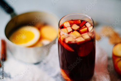 Photos Hot mulled wine in a glass with orange slices, anise and cinnamon sticks, star cookies on vintage wood table
