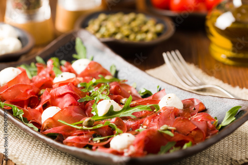 Beef carpaccio served with balls of mozzarella cheese, arugula and capers.