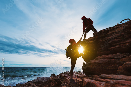 Young asian couple climbing up on the mountain,hiking and team work concept. photo