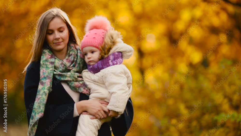 in autumn, when yellow leaves around mom and girl playing with maple leaves, laughing and smiling. Mom hugs and plays with my daughter in the fall. Bokeh and sunlight. in autumn, when yellow leaves around mom and girl playing with maple leaves, laughing and smiling. Mom hugs and plays with my daughter in the fall. Bokeh and sunlight.