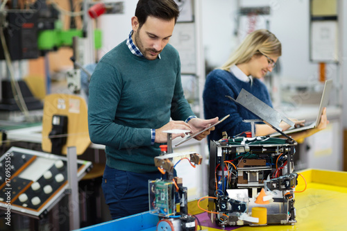 Young students of robotics preparing robot for testing