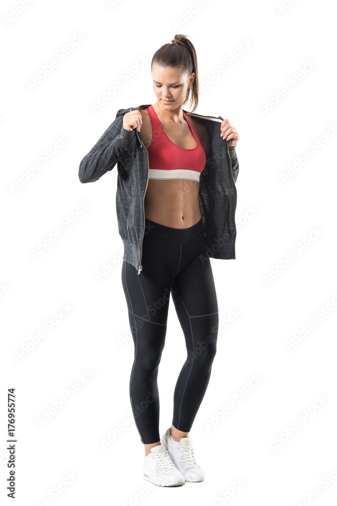 Young sport fitness woman get dressed in hooded sweatshirt for autumn outdoor running. Full body length portrait isolated on white background.