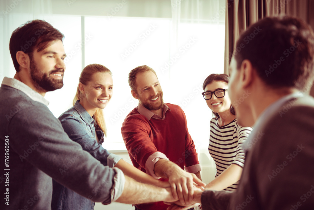 Obraz premium Positive cheerful team standing in the circle