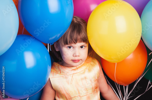 Little girl with colorful balloons over black