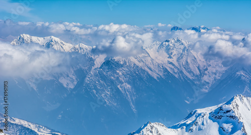 Alpine landscape with peaks covered by snow and clouds © olenatur