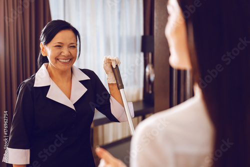 Positive delighted chambermaid looking at her guest