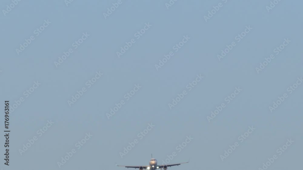 Large airplane approaches and crosses a flock of birds, with front view and blue sky. Large airplane approaches and crosses a flock of birds, with front view and blue sky.