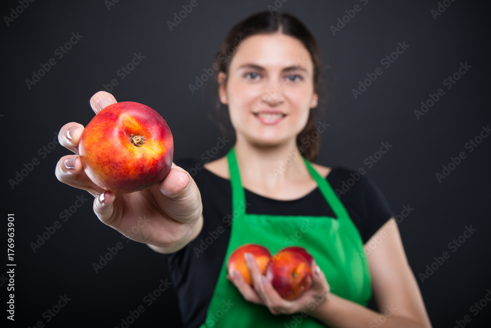 Girl employee holding organic nectarine in closeup Girl employee holding organic nectarine in closeup