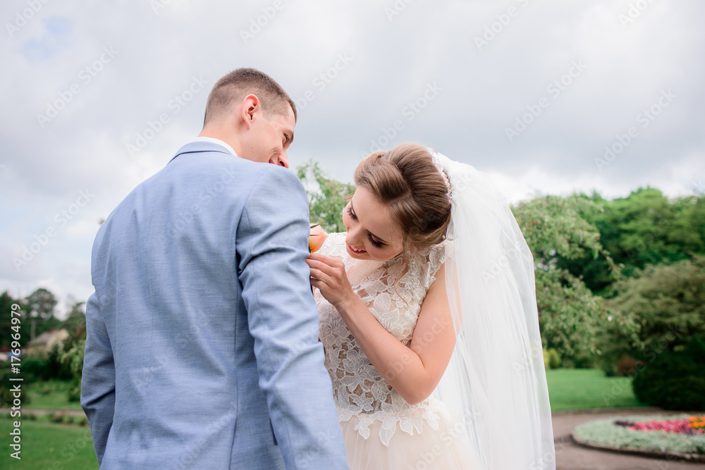 Bride pins boutonniere to groom's jacket Bride pins boutonniere to groom's jacket