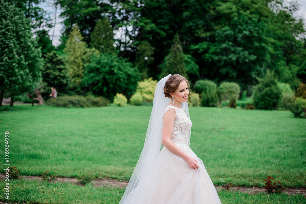Tender young bride walks in white dress around the park