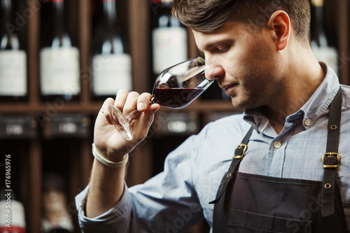 Bokal of red wine on background, male sommelier appreciating drink photo