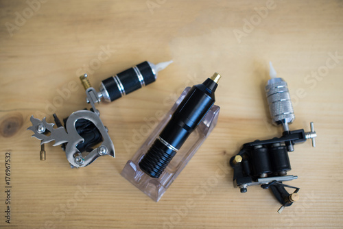 Three different custom professional tattoo guns arranged on a wooden table top view. photo