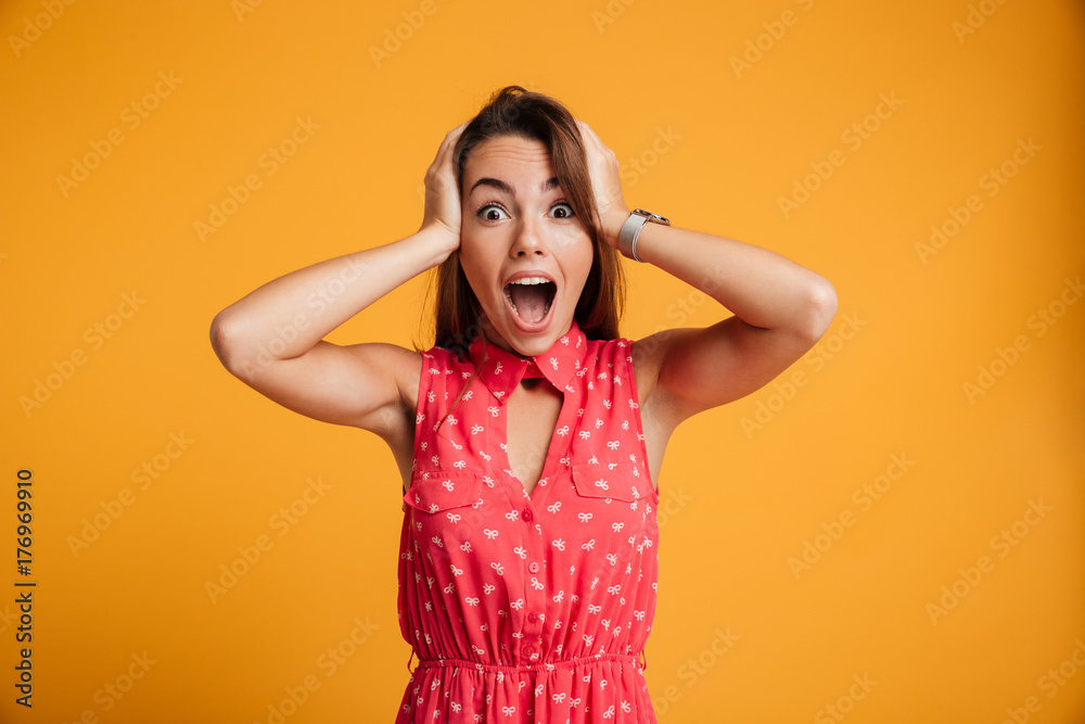 Portrait of happy surprised young woman in red dress standing with open mouth, touching head Portrait of happy surprised young woman in red dress standing with open mouth, touching head