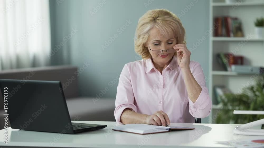 Mature woman creating shopping list, writing plans in notepad, busy housewife Mature woman creating shopping list, writing plans in notepad, busy housewife