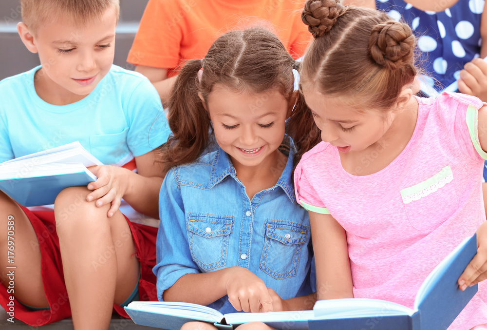 Cute little children reading books outdoors Cute little children reading books outdoors