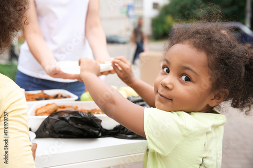 Volunteer sharing food with poor African child outdoors