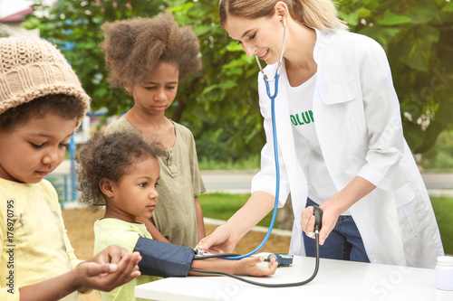 Volunteer doctor measuring blood pressure of poor African child outdoors