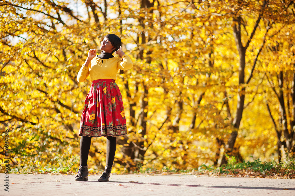 African american girl at yellow and red dress at golden autumn fall park. African american girl at yellow and red dress at golden autumn fall park.